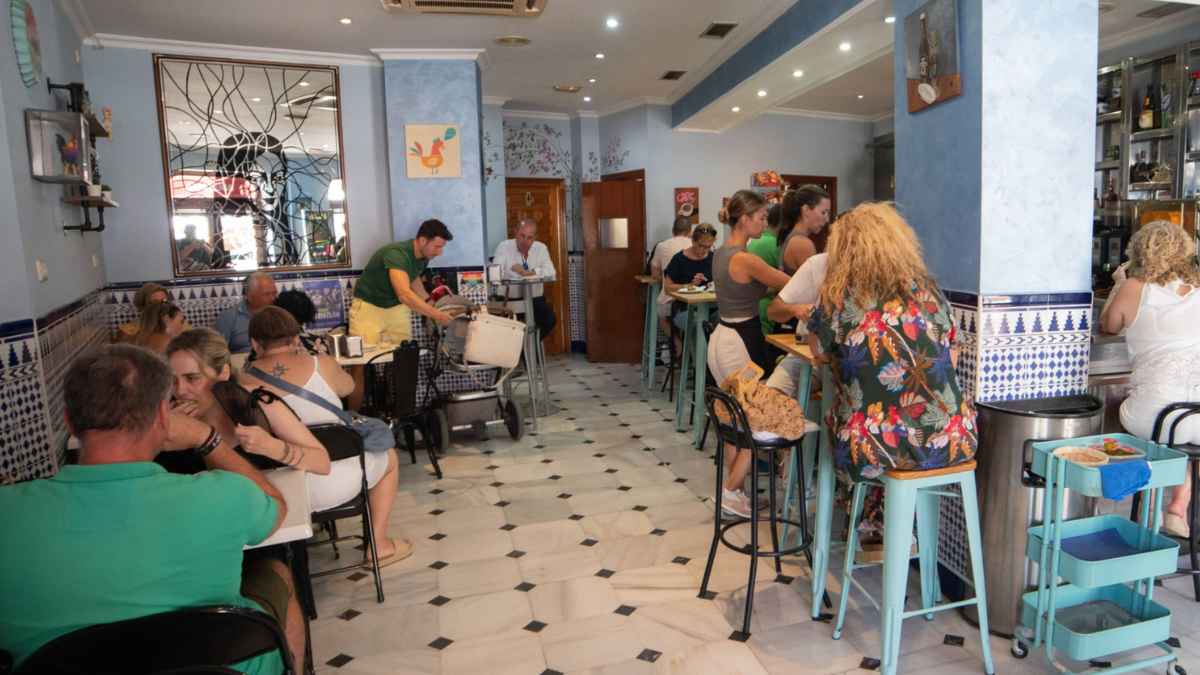 Interior de un bar español con clientes conversando y camareros atendiendo en la barra, reflejando la actividad diaria de la hostelería