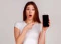 Joven sorprendida señala su iPhone con la pantalla vacía tras perder WhatsApp por no actualizar a iOS 15 .1
