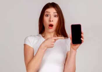 Joven sorprendida señala su iPhone con la pantalla vacía tras perder WhatsApp por no actualizar a iOS 15 .1