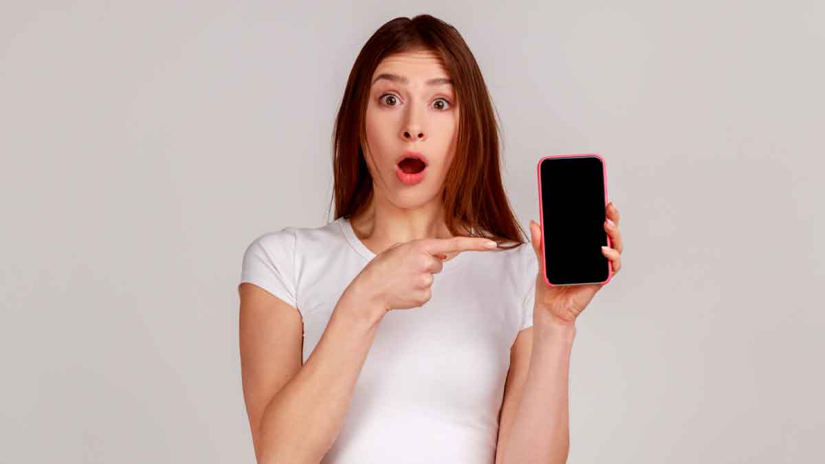 Joven sorprendida señala su iPhone con la pantalla vacía tras perder WhatsApp por no actualizar a iOS 15 .1