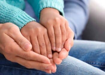 Manos de un adulto sosteniendo las de un niño, símbolo de la adopción en la Comunidad de Madrid 2025