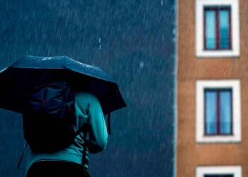 Persona con paraguas bajo lluvia intensa en Madrid, según previsión de la AEMET para el fin de semana