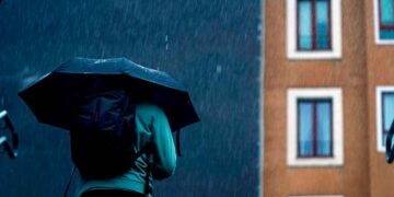 Persona con paraguas bajo lluvia intensa en Madrid, según previsión de la AEMET para el fin de semana