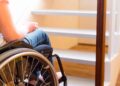 Persona en silla de ruedas frente a escalera dentro de una vivienda, ejemplo de accesibilidad en el hogar en Madrid