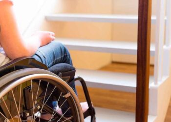 Persona en silla de ruedas frente a escalera dentro de una vivienda, ejemplo de accesibilidad en el hogar en Madrid