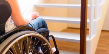 Persona en silla de ruedas frente a escalera dentro de una vivienda, ejemplo de accesibilidad en el hogar en Madrid