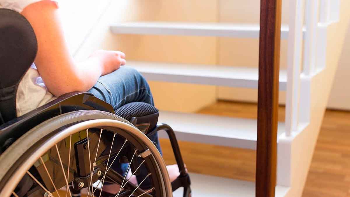 Persona en silla de ruedas frente a escalera dentro de una vivienda, ejemplo de accesibilidad en el hogar en Madrid