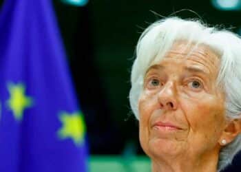 Primer plano de una alta funcionaria del Banco Central Europeo ante la bandera de la UE durante el anuncio de una próxima bajada de tipos de interés