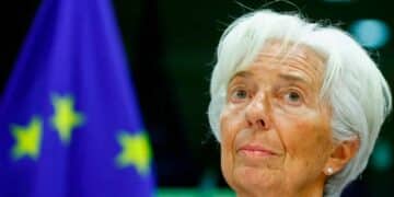 Primer plano de una alta funcionaria del Banco Central Europeo ante la bandera de la UE durante el anuncio de una próxima bajada de tipos de interés