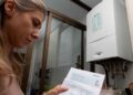 Mujer madrileña revisa una factura de gas Naturgy junto a su caldera doméstica, ilustrando el Bono Social Térmico 2025 en Madrid