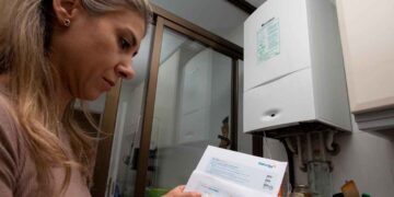 Mujer madrileña revisa una factura de gas Naturgy junto a su caldera doméstica, ilustrando el Bono Social Térmico 2025 en Madrid
