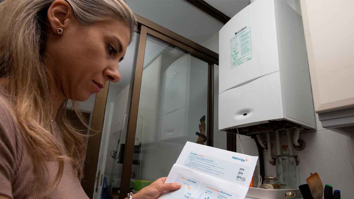 Mujer madrileña revisa una factura de gas Naturgy junto a su caldera doméstica, ilustrando el Bono Social Térmico 2025 en Madrid