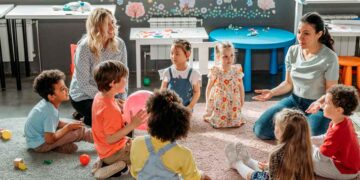 Niños y educadoras sentados en círculo en una escuela infantil privada de Madrid, ejemplo del Cheque Guardería 2025-2026