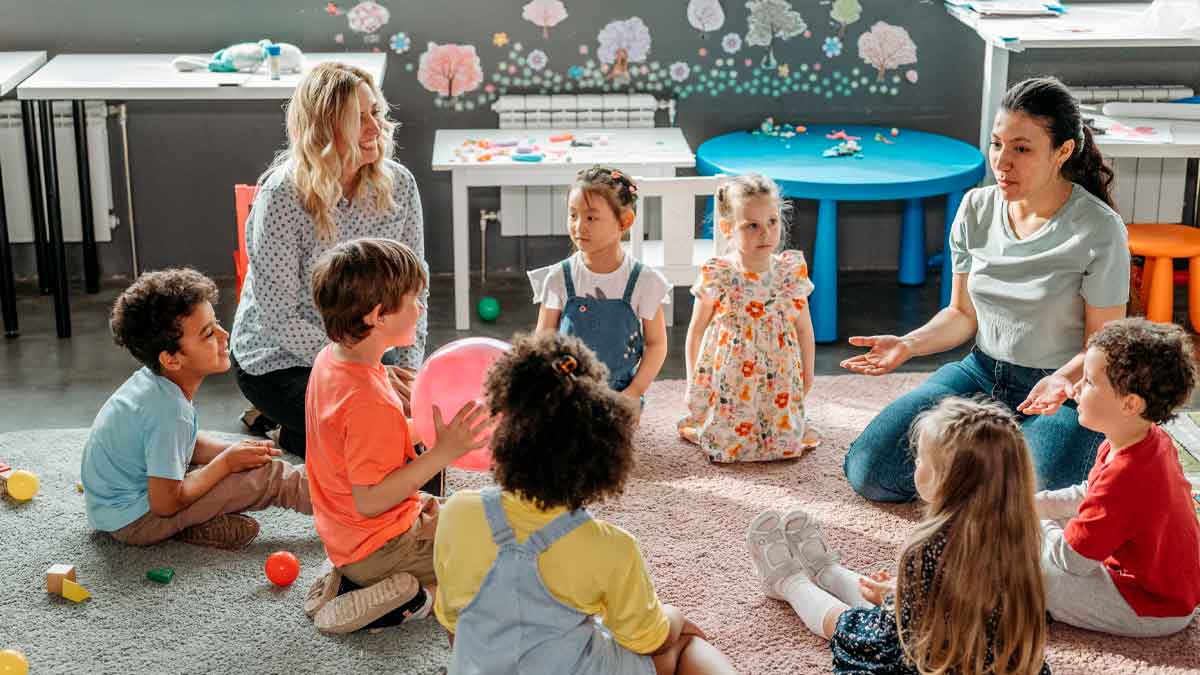 Niños y educadoras sentados en círculo en una escuela infantil privada de Madrid, ejemplo del Cheque Guardería 2025-2026