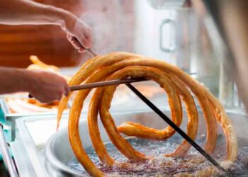 Churrero de Marbella elaborando una gran rueda de churros en aceite, implicado en el robo de 86 000 euros con un truco de caja