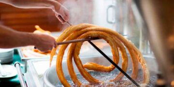 Churrero de Marbella elaborando una gran rueda de churros en aceite, implicado en el robo de 86 000 euros con un truco de caja