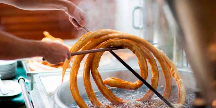 Churrero de Marbella elaborando una gran rueda de churros en aceite, implicado en el robo de 86 000 euros con un truco de caja
