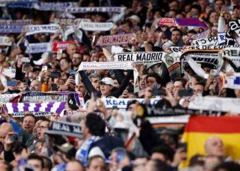 Aficionados del Real Madrid levantan bufandas y móviles en el Santiago Bernabéu, ambiente de grada que disfrutan los socios del club