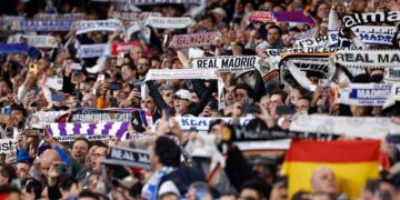 Aficionados del Real Madrid levantan bufandas y móviles en el Santiago Bernabéu, ambiente de grada que disfrutan los socios del club