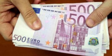 Billetes de 500 € en manos, representando la ayuda de 10.980 € del SEPE para desempleados con cotización insuficiente