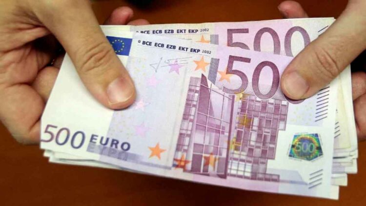 Billetes de 500 € en manos, representando la ayuda de 10.980 € del SEPE para desempleados con cotización insuficiente