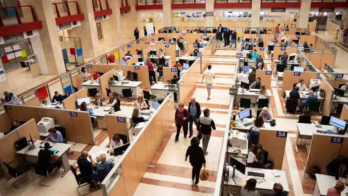 Oficina de la Agencia Tributaria llena de contribuyentes preparando y presentando la declaración de la Renta 2024/25 antes de la fecha límite