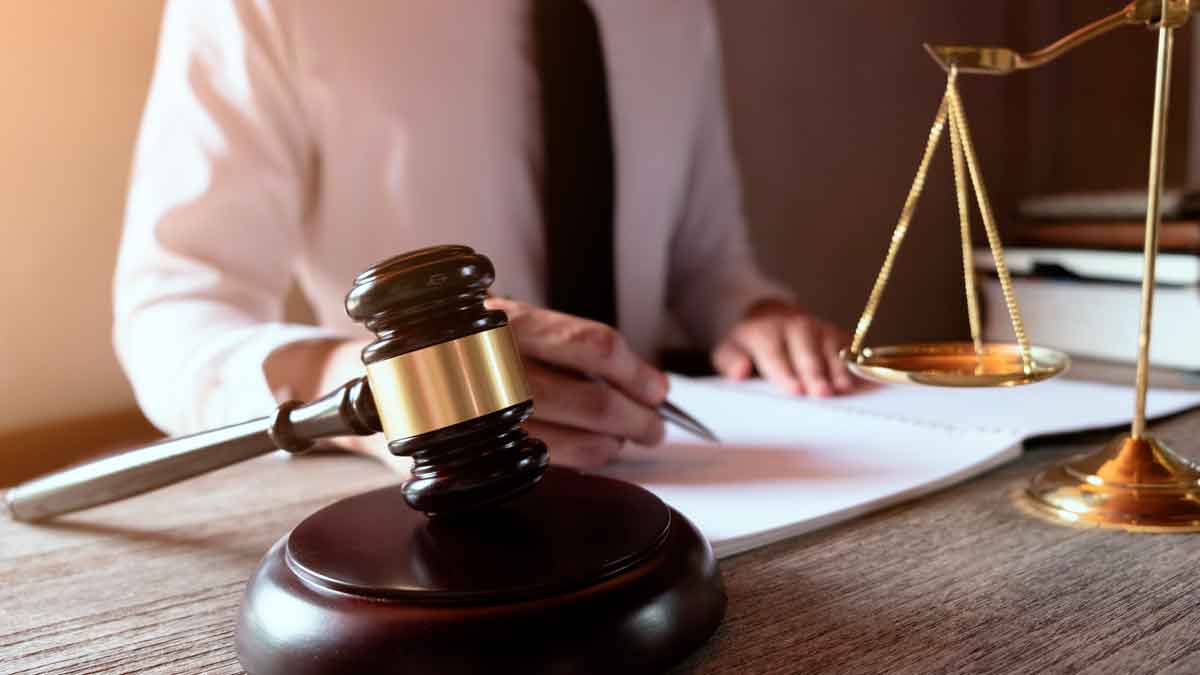 Mazo y balanza ante abogado redactando sentencia del Tribunal Supremo que anula el cambio de jornada a fines de semana