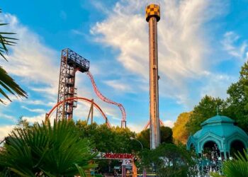 Torre de caída libre y montaña rusa del Parque de Atracciones de Madrid al atardecer, vistas desde la zona de acceso principal