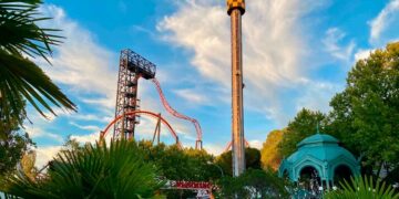Torre de caída libre y montaña rusa del Parque de Atracciones de Madrid al atardecer, vistas desde la zona de acceso principal