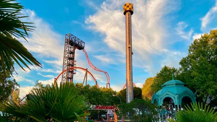 Torre de caída libre y montaña rusa del Parque de Atracciones de Madrid al atardecer, vistas desde la zona de acceso principal