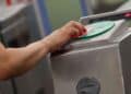 Mano de usuario validando la tarjeta de transporte en un lector del Metro de Madrid