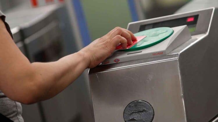 Mano de usuario validando la tarjeta de transporte en un lector del Metro de Madrid