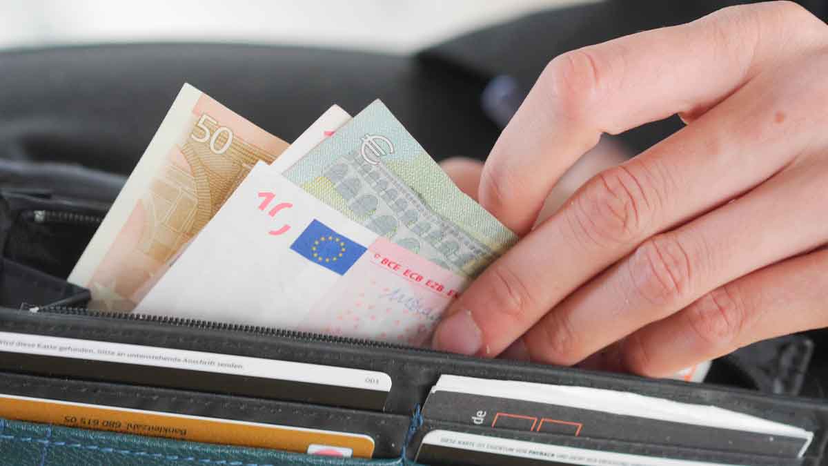 Mano extrayendo varios billetes de euro de una cartera, símbolo del límite de 100.000 € en efectivo impuesto por Hacienda