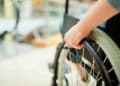 Trabajador en silla de ruedas ajusta la rueda: fin del despido automático por incapacidad permanente Ley 2/2025