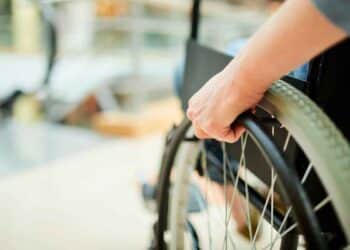 Trabajador en silla de ruedas ajusta la rueda: fin del despido automático por incapacidad permanente Ley 2/2025