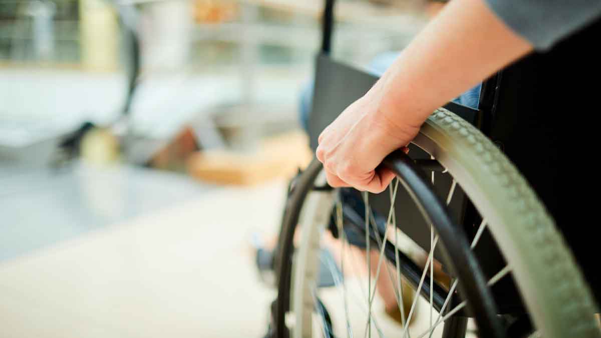 Trabajador en silla de ruedas ajusta la rueda: fin del despido automático por incapacidad permanente Ley 2/2025