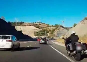 Motociclista circulando por el arcén en una autovía con tráfico denso, novedad normativa DGT 2025 sobre carril izquierdo