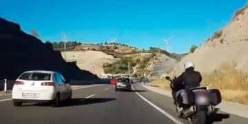 Motociclista circulando por el arcén en una autovía con tráfico denso, novedad normativa DGT 2025 sobre carril izquierdo