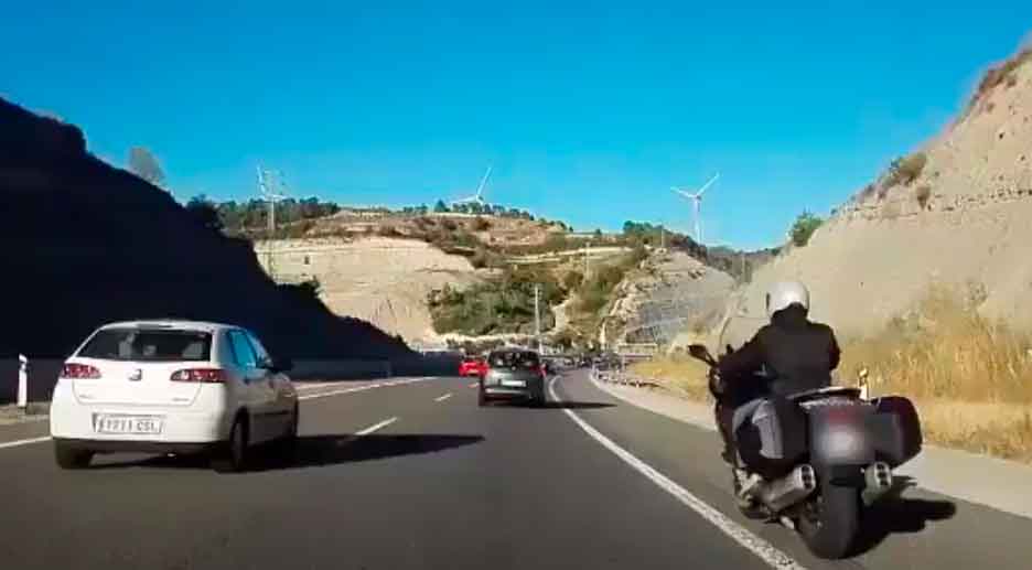 Motociclista circulando por el arcén en una autovía con tráfico denso, novedad normativa DGT 2025 sobre carril izquierdo