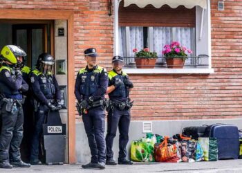 Policías municipales vigilan la entrada de una vivienda social con maletas y bolsas en la acera durante un desahucio por ocupación ilegal en Madrid