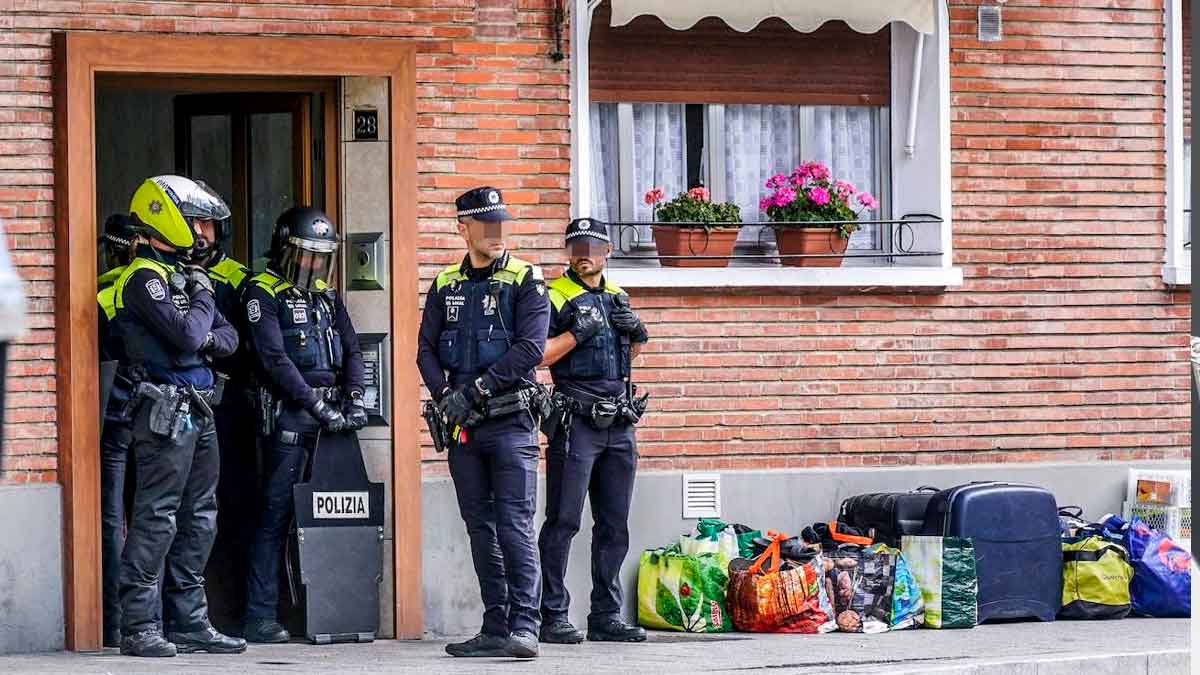 Policías municipales vigilan la entrada de una vivienda social con maletas y bolsas en la acera durante un desahucio por ocupación ilegal en Madrid