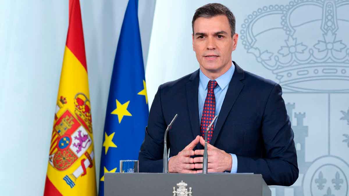 Presidente del Gobierno español anunciando el Plan VEO con banderas de España y la Unión Europea al fondo, frente a un atril oficial