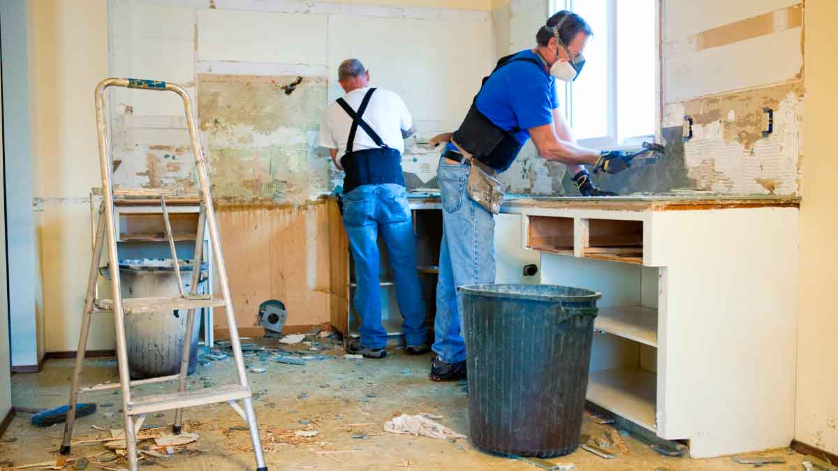 Dos operarios reforman una cocina antigua, paso esencial para ahorrar IVA en la reforma de la vivienda y ajustar el presupuesto