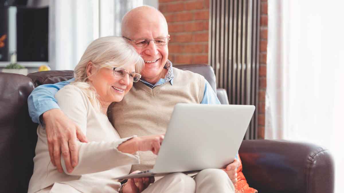 Pareja de jubilados sonríe mientras revisa en un portátil la eliminación de penalizaciones por jubilación anticipada con 40 años cotizados