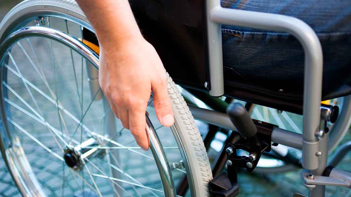 Detalle de una mano impulsando la rueda de una silla de ruedas, símbolo de la protección frente al despido por incapacidad sobrevenida