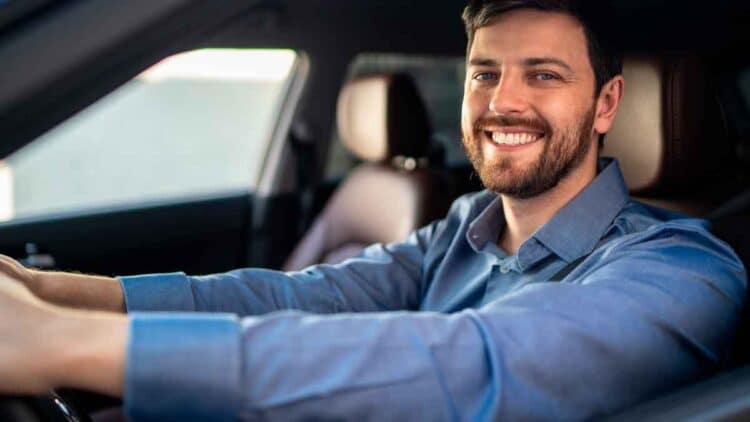Conductor sonriente dentro de su coche tras conocer la sentencia que anula intereses abusivos en créditos de vehículo