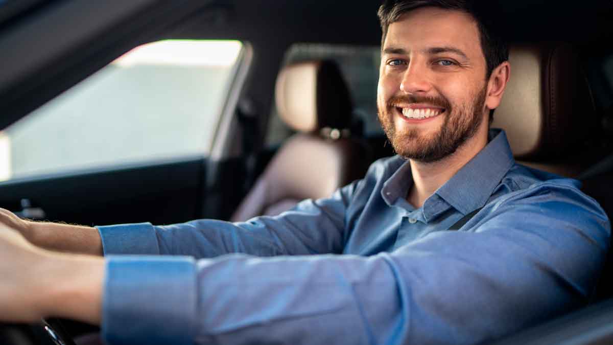 Conductor sonriente dentro de su coche tras conocer la sentencia que anula intereses abusivos en créditos de vehículo