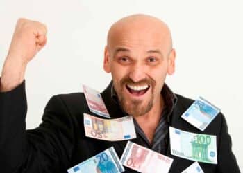 Hombre calvo sonriente cubierto de billetes de euro, simbolizando la ayuda de 600 € del SEPE por completar cursos oficiales