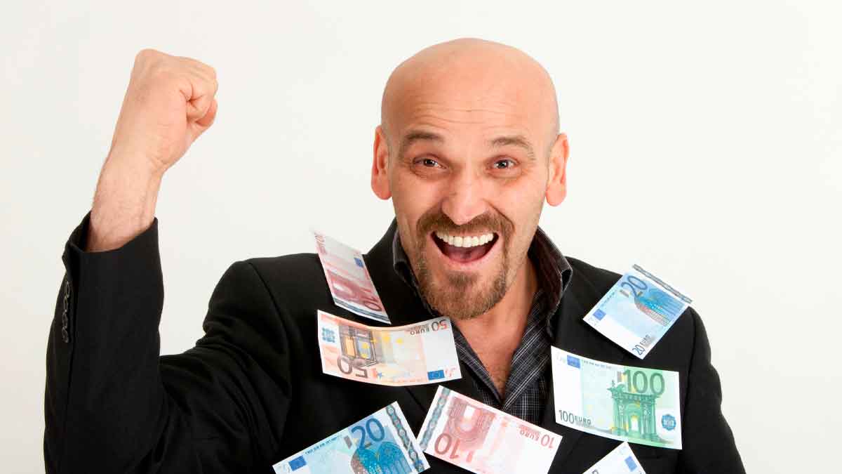 Hombre calvo sonriente cubierto de billetes de euro, simbolizando la ayuda de 600 € del SEPE por completar cursos oficiales