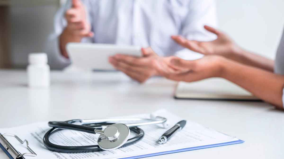Consulta médica con doctor y paciente; un estetoscopio sobre documentos simboliza la baja que resta meses de paro según el SEPE